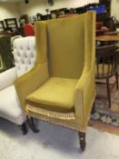 A late Regency upholstered wing back armchair on turned and ringed front legs to brass caps and
