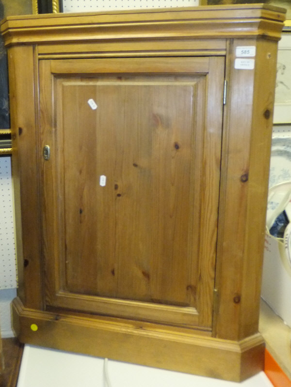 A pine hanging corner cupboard with single panelled door