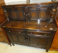 A dark elm Ercol court cupboard with plate rack above two cupboard doors with two drawers and two