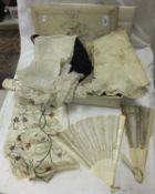 An embroidered fabric covered box containing a collection of fans, lace and embroidered fabric
