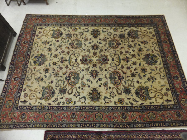 A Tabriz carpet, the central cream field with stylised floral decoration in blue, red, green and