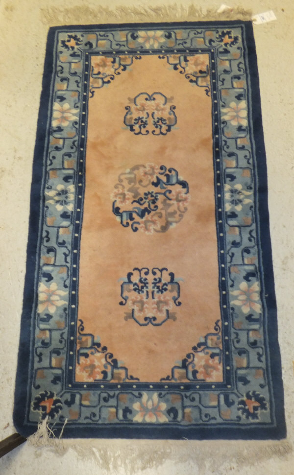 A Chinese rug, the three central floral medallions on a peach ground within a blue, cream and
