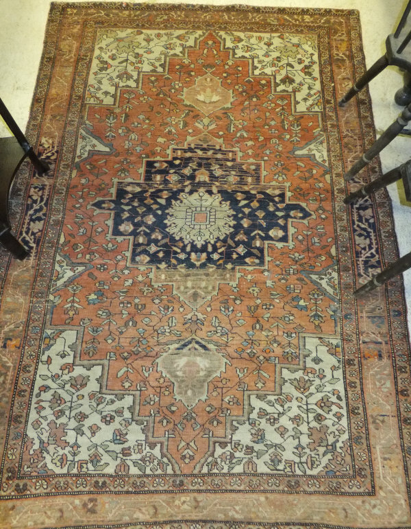 A Persian rug, the central panel set with floral decorated medallion on a red ground within a