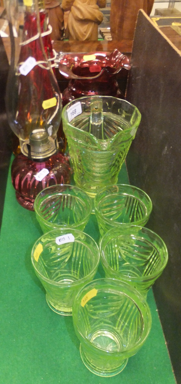 A vaseline glass lemonade set of jug and five glasses, a cranberry glass jug, oil lamp with