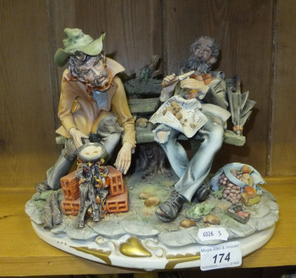 A capo-di-monte figure group "Good Heart" depicting two men on a bench, one cooking eggs in a pan