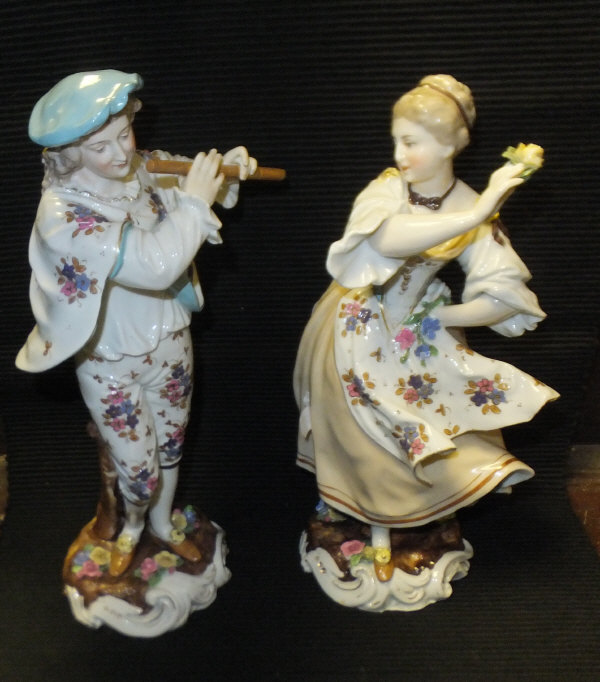 A pair of Dresden porcelain figures of a young man playing pipe and woman dancing with flower in her