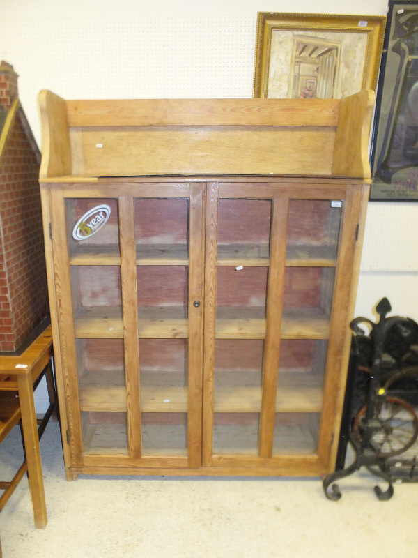 A pine cabinet with two glazed doors enclosing shelves