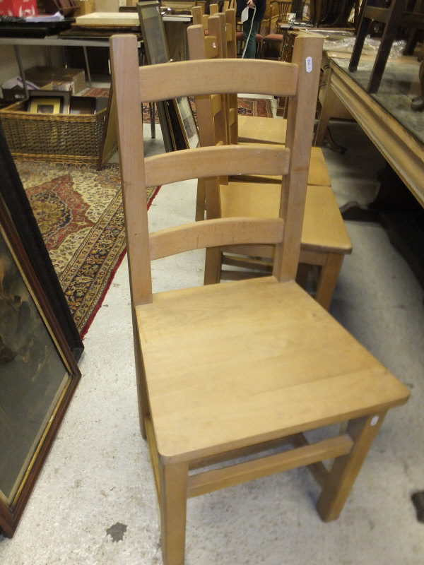 A set of four modern beech ladder back panel seat dining chairs