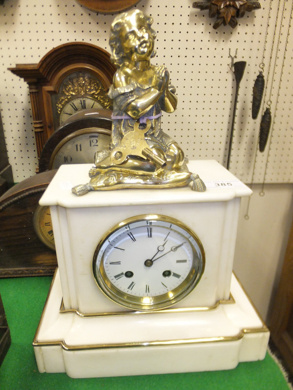 A late Victorian polished alabaster cased and brass mounted mantel clock with figural surmount of