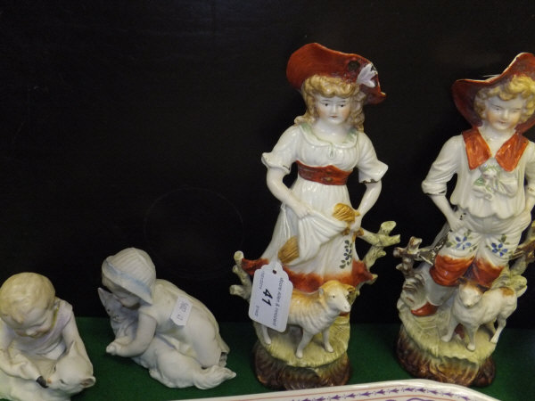 A pair of 19th Century style figures in 18th Century dress with attendant sheep, together with a