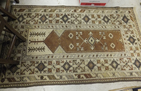 A Turkish prayer rug with brown and ochre motifs on a cream ground, 205 cm x 115 cm
