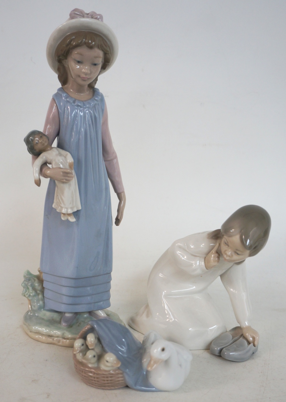 THREE LLADRO FIGURINES
depicting a goose with her goslings in a basket, a young girl holding a