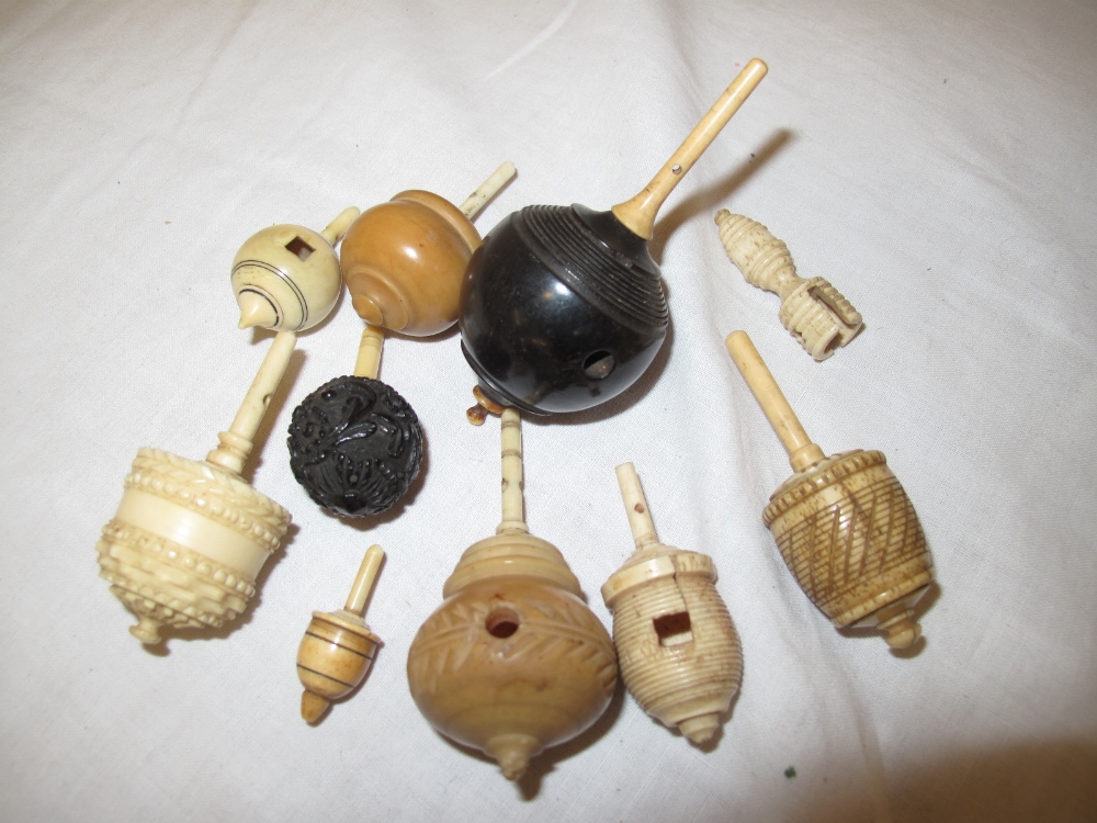 Nine 19thC humming tops made from ivory, bone, horn and hardwood. together with a holder