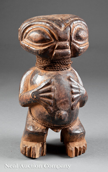 An African Carved Wood Figure, squatting male nude carved with flattened bulbous head, exaggerated