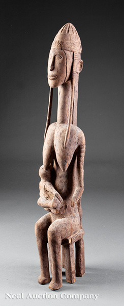 An Igbo Carved Wood Ancestor Figure with Child, Nigeria, seated female nude carved with an elongated