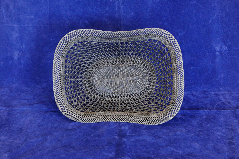 A white metal wirework basket raised on an oval foot. 12½ by 9ins.