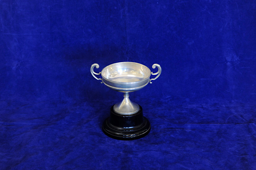 An Edward VII silver twin handled trophy cup, on a slender tapering stem and ebonised base.