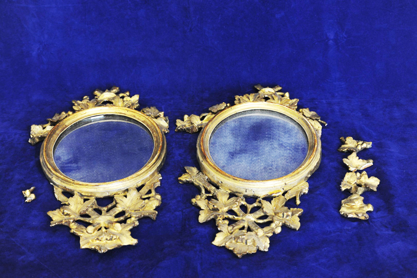 A pair of 19th century oval wall mirrors, the gilt frames with leaf and fruit decoration (af). 9½ by