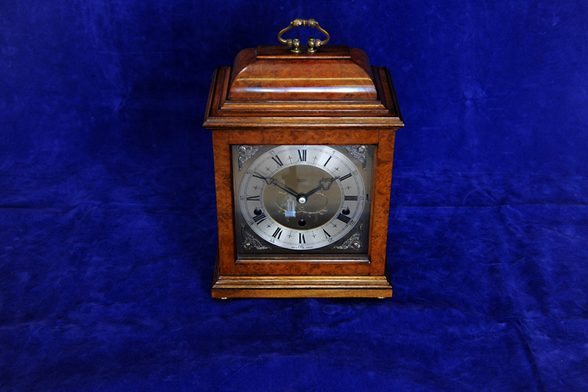 A reproduction walnut cased mantel clock with pagoda top, swing brass carrying handle. The dial with