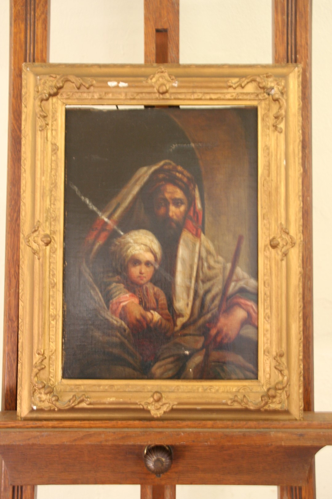 An oil on canvas of a Middle Eastern gentleman wearing a headscarf holding his son. 9¾ by 13½ins. In