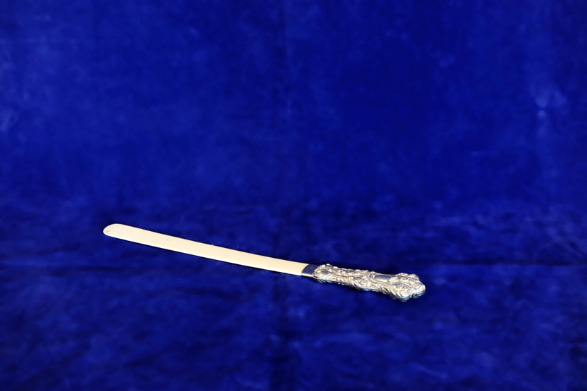 A late Victorian silver handled paperknife with ivory lower section and with cast rococo scroll