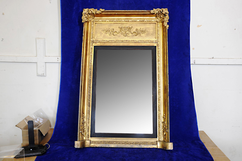 An 18th century gilt framed wall mirror with silvered back plate, ebonised reeded slip and floral