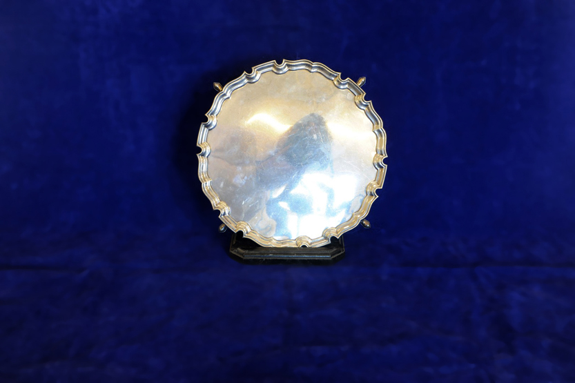 A George V silver salver with gadrooned rim and raised on four pad feet with presentation