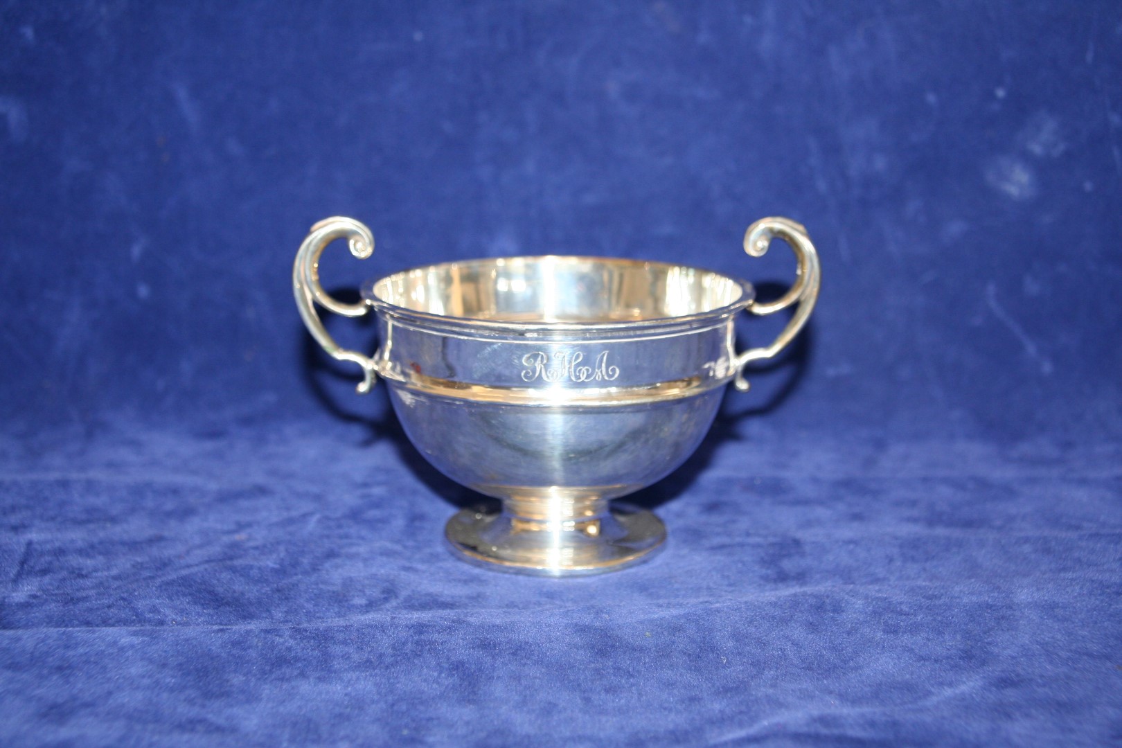 A George V silver twin handled bowl with double scroll handle, on a slender stem and circular