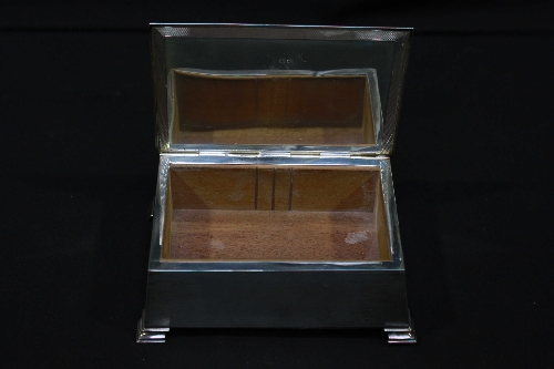 A silver cigarette box of rectangular form, with sloped sides, raised on bracket feet, with cast - Image 2 of 2