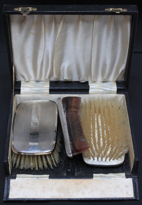 A gentleman`s pair of silver backed hair brushes and a silver mounted comb with case.