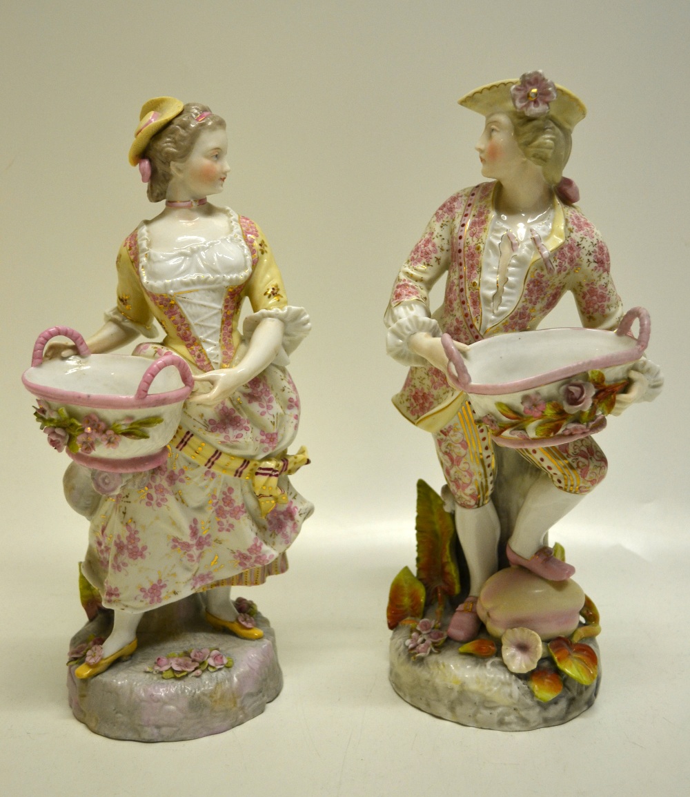 A pair of nineteenth century French porcelain figures salts of a gallant and his lass holding oval