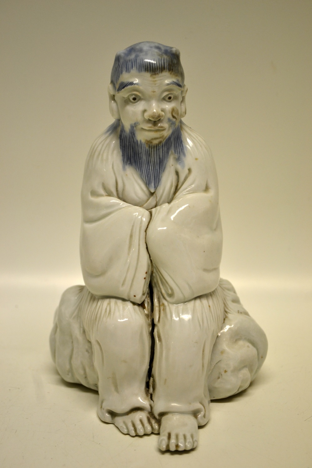 An early nineteenth century Japanese blue and white porcelain Oni, seated on a rock with his arms