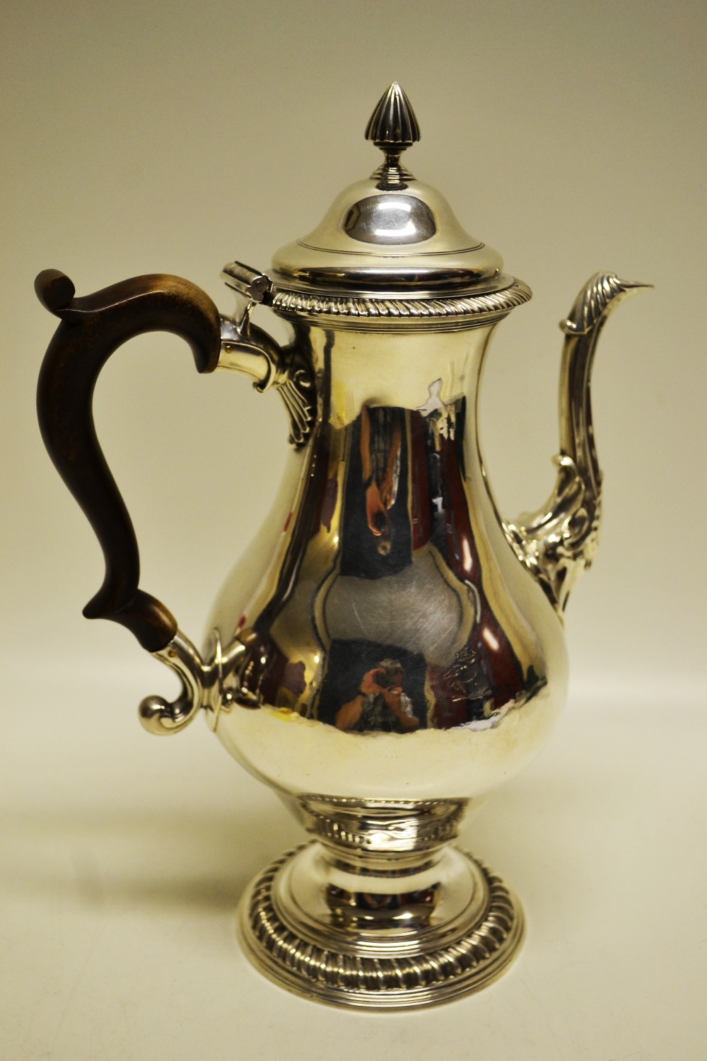 A George III silver coffee pot, the crested baluster body with a cast rococo cartouche, a moulded