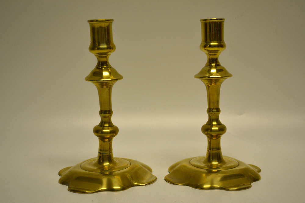 A pair of George II brass candlesticks, the knopped stems on petal moulded welled bases. 6.75in (