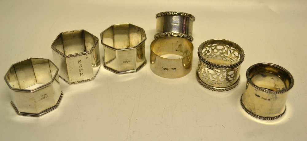 A pair of Edwardian silver octagonal napkin rings, a hexagonal napkin ring with initials, a bead