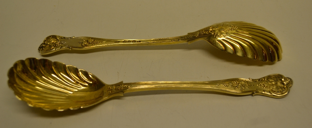 A pair of Victorian silver gilt vine pattern dessert serving spoons with shell fluted oval bowls.