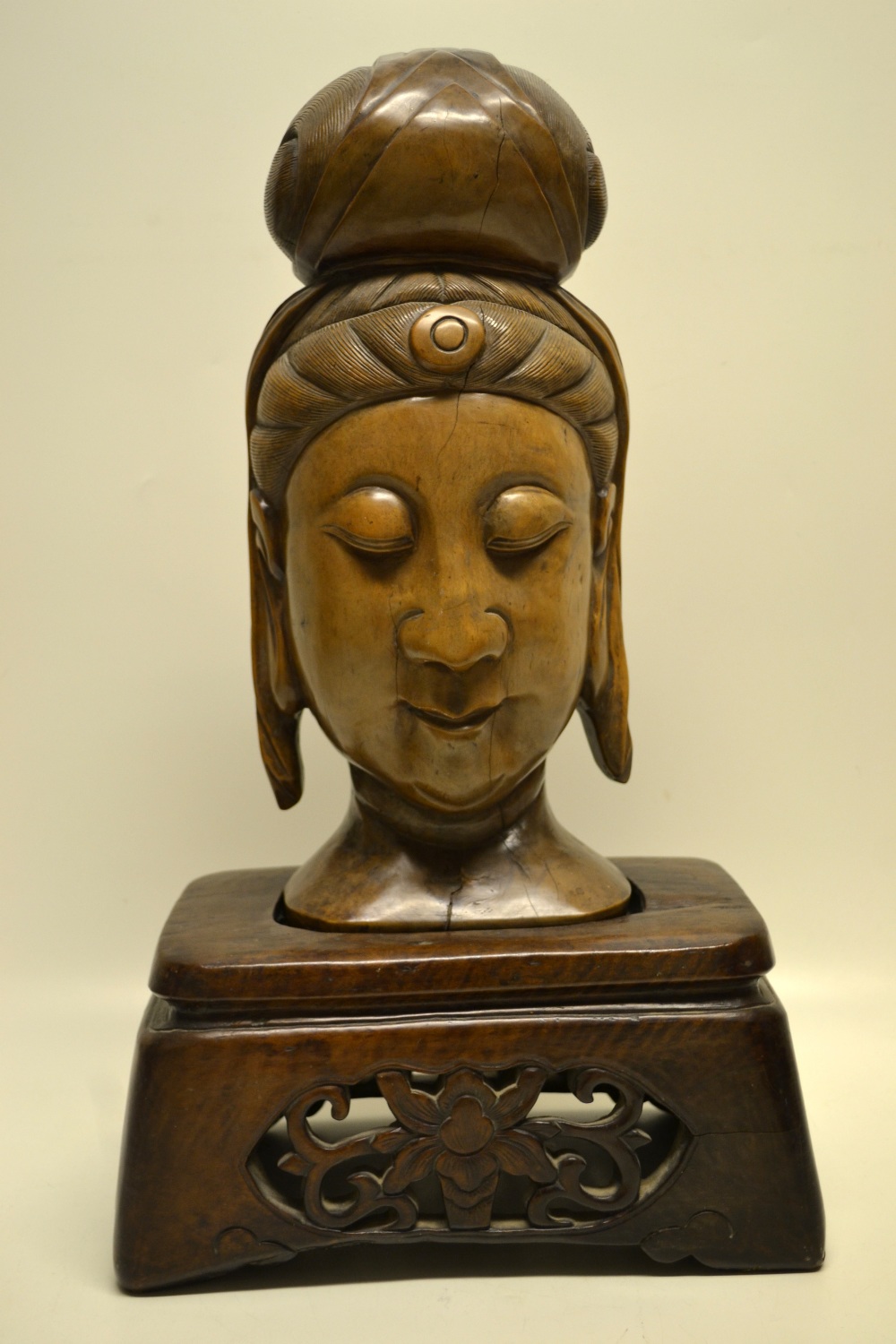 A Burmese carved teak Bhuddha`s head, on a rectangular stand with pierced carved foliage. Late