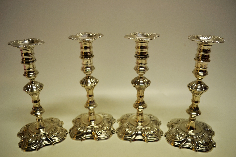 A set of four cast George II silver candlesticks, having panelled waisted stems, the spool shape