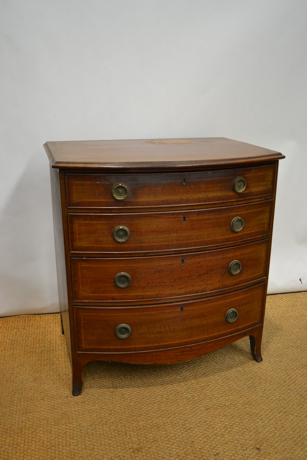 A late nineteenth century Sheraton Revival small mahogany bow front chest, inlaid chequer banding,