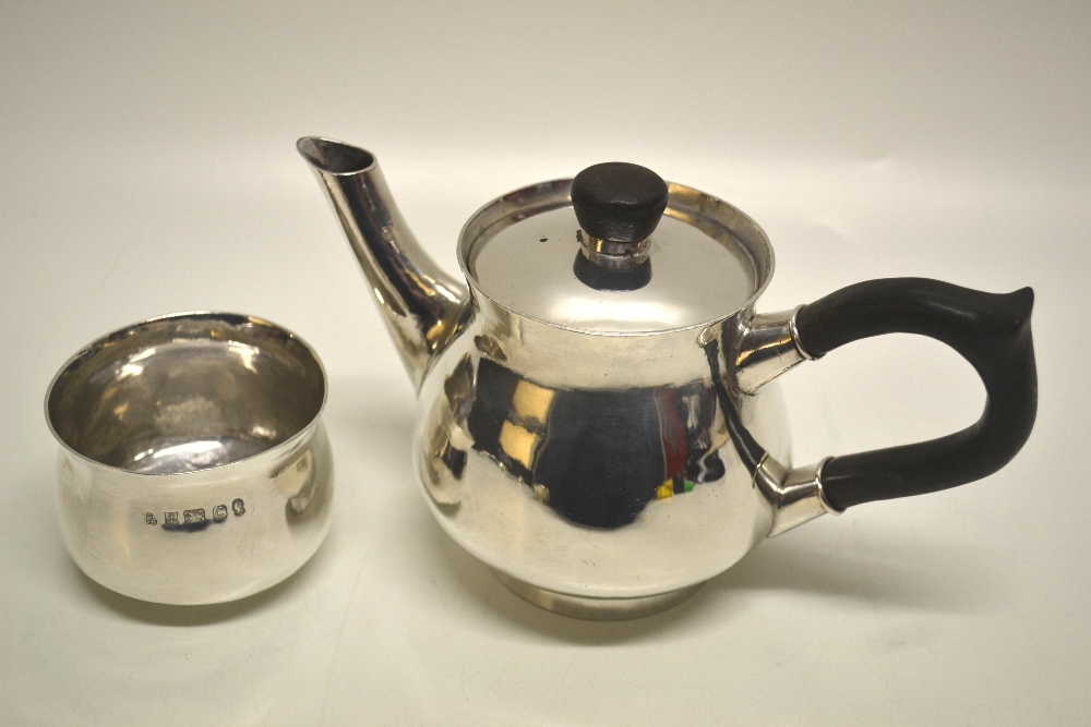 A modern design silver teapot, the swelling body with a scroll spout, the flange with a detachable