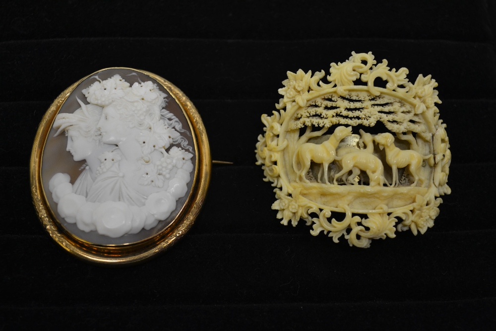 A Victorian pierced carved ivory brooch of hounds beneath an arbour and an oval double portrait