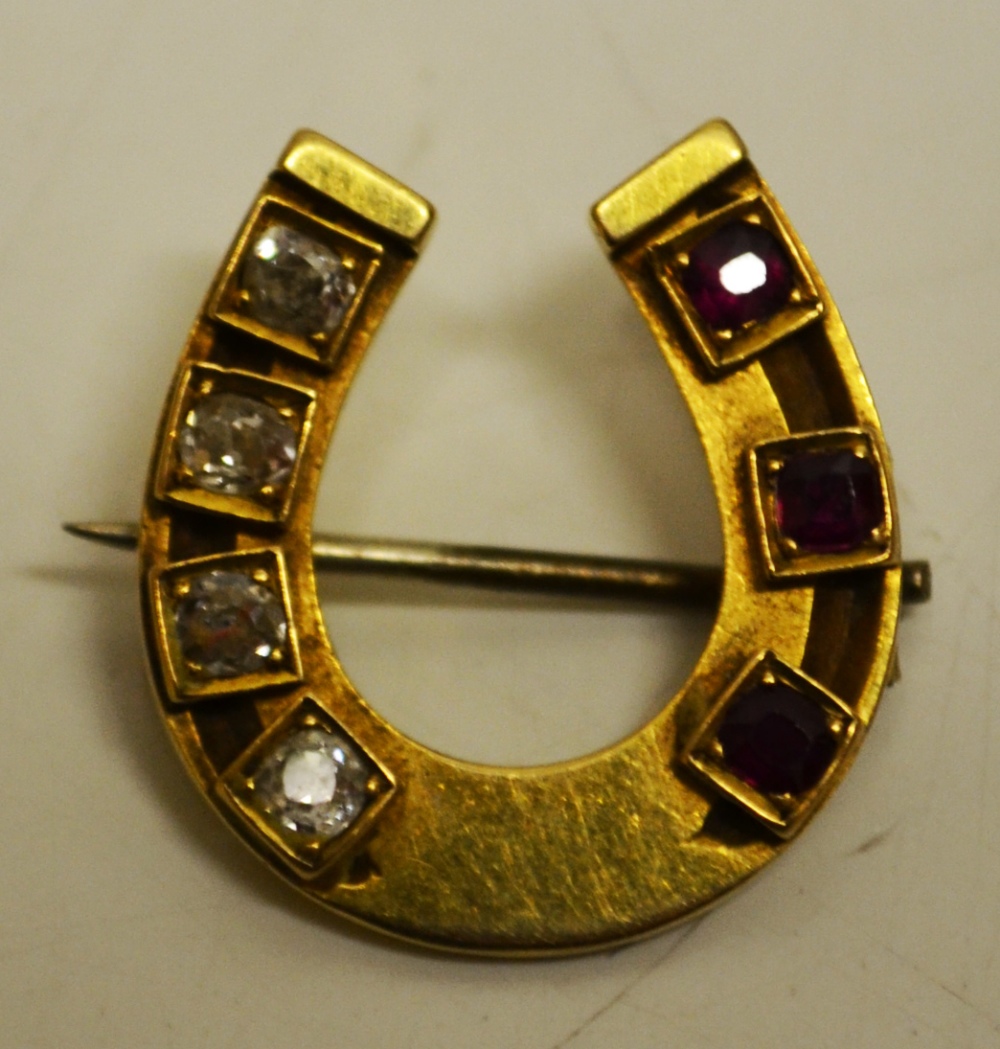 A late Victorian gold horseshoe brooch, set rubies and diamonds.