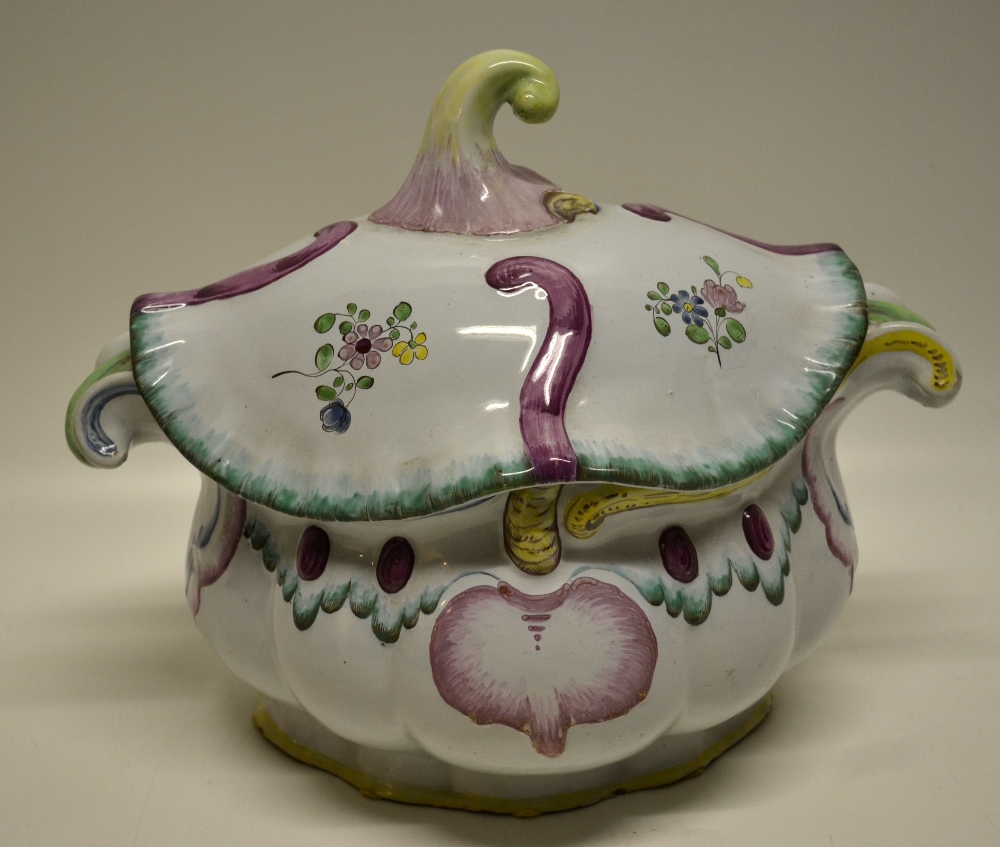 A French Faience rococo oval tureen, with cover, having scroll lifts, floral scroll coloured