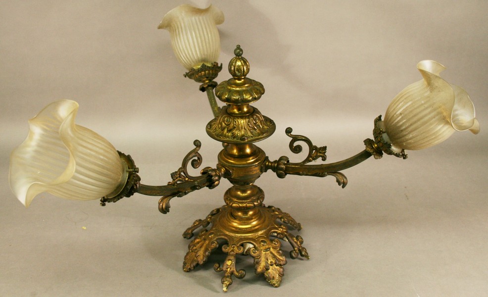 A GILT METAL ELECTRICAL LIGHT FITTING having a foliate crown and turned column with three scrolling