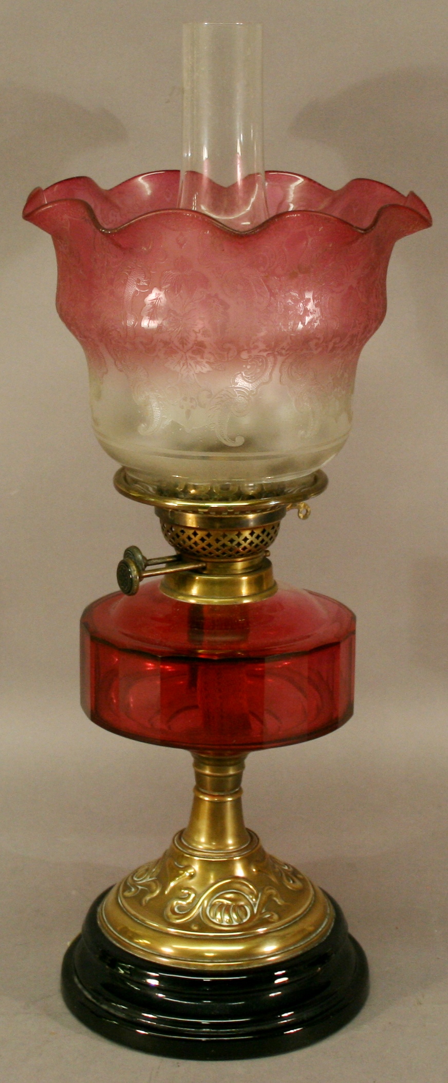 A VICTORIAN BRASS AND GLASS OIL LAMP having a frosted etched glass shade with waved cranberry