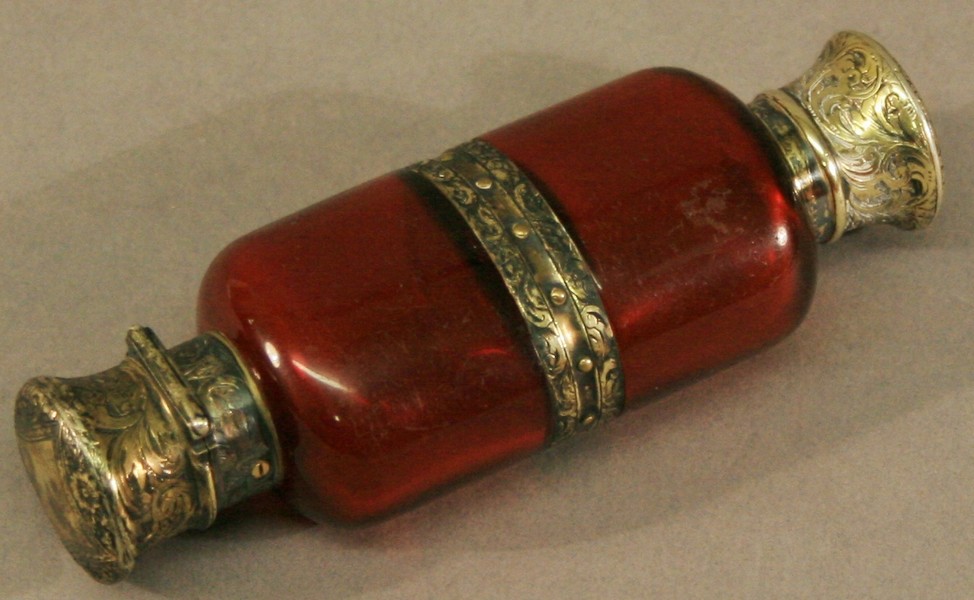 A 19TH CENTURY WHITE METAL-MOUNTED DOUBLE RUBY GLASS SCENT BOTTLE by S. Mordan & Co, with foliate