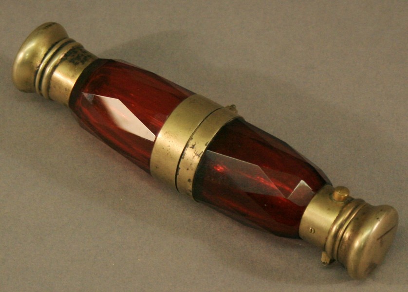 A VICTORIAN WHITE METAL MOUNTED RUBY GLASS DOUBLE SCENT BOTTLE, the faceted ruby glass bottles