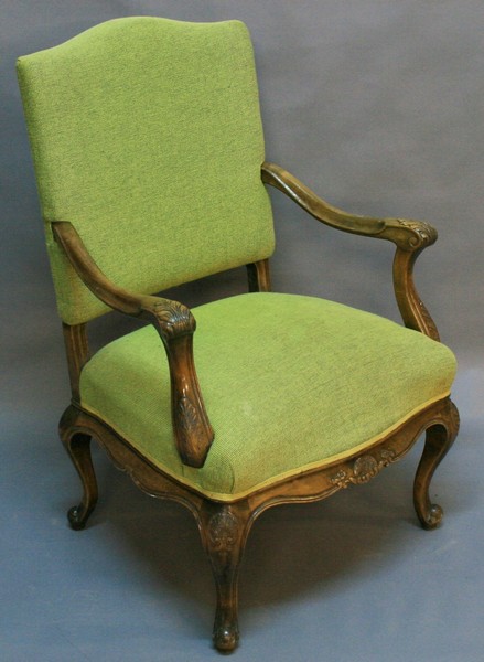 AN EARLY 20TH CENTURY OPEN ARMCHAIR having a humped padded back, shaped and scrolled open arms with