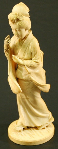 A JAPANESE CARVED IVORY OKIMONO Meiji Period, carved as a female in traditional dress, the oval