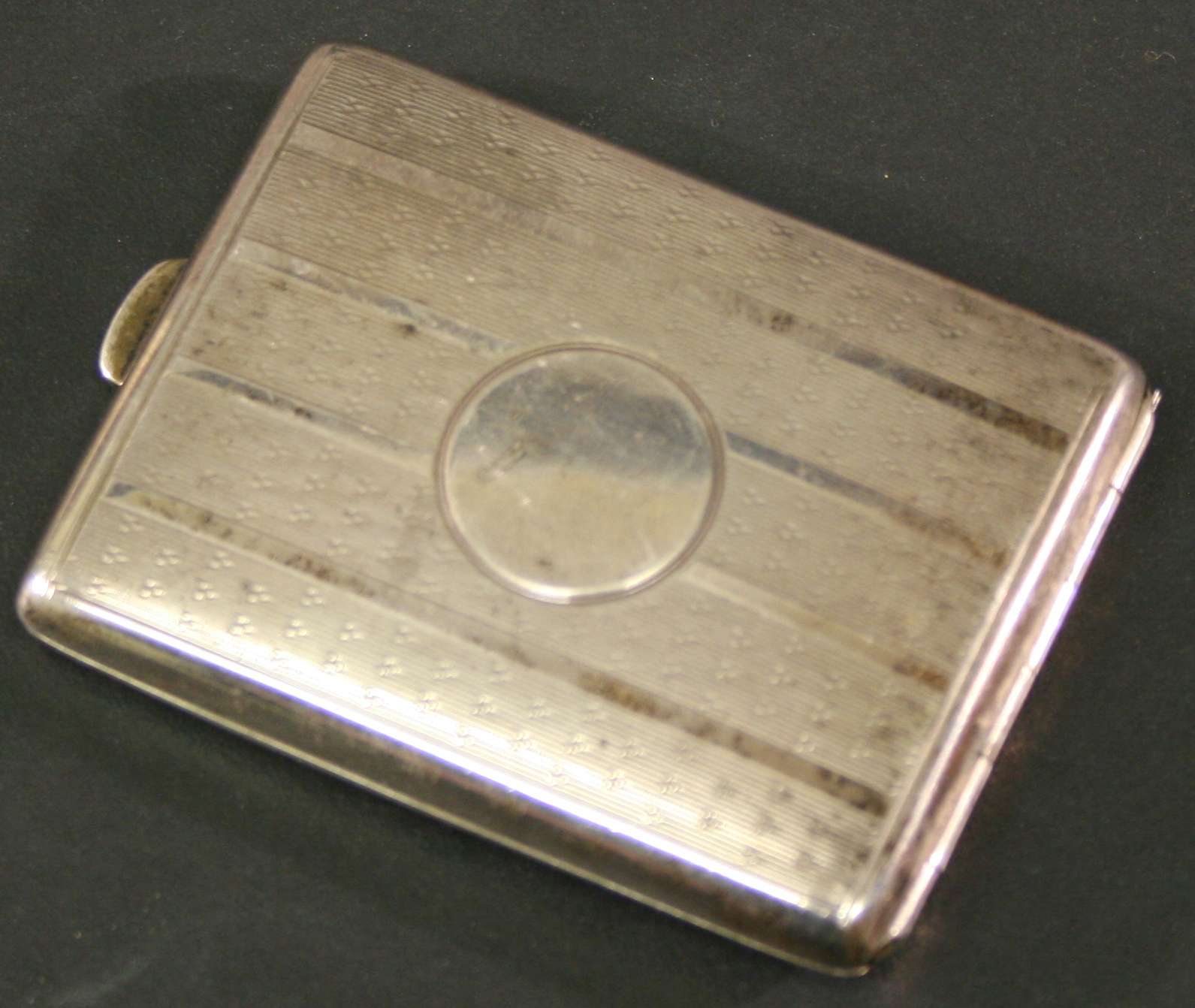 A GEORGE V SILVER MATCHBOOK HOLDER of hinged rectangular form with central circular cartouche and